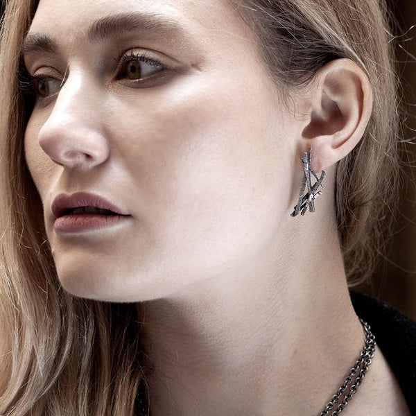 young woman wearing a black silver earring made of asymmetrical twigs