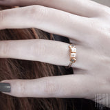 woman's hand wearing a white and red gold ring with rectangle diamonds