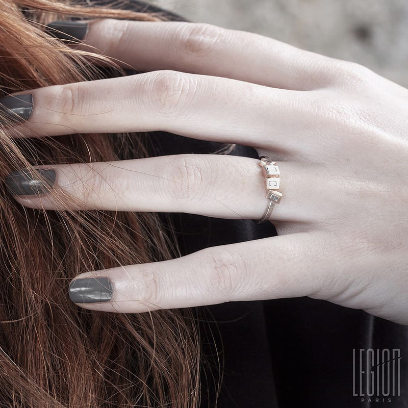 red-haired woman's hand with grey nails wearing a fine white and red gold and diamond ring