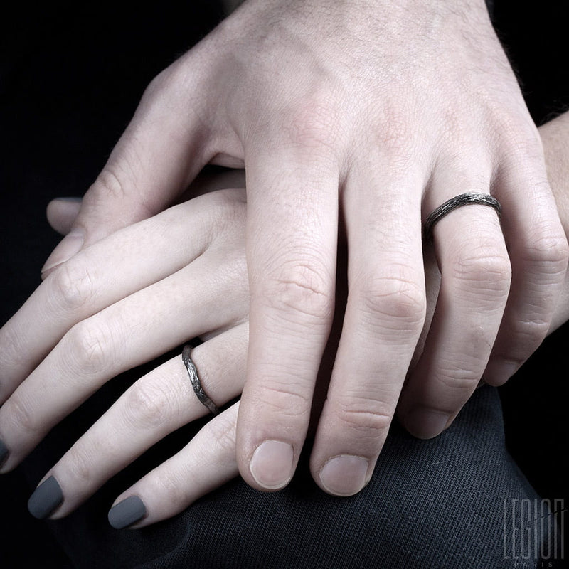 women's and men's hands wearing textured black gold wedding rings