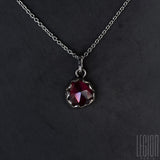 close-up of a red garnet set in white gold with a white gold forçat chain
