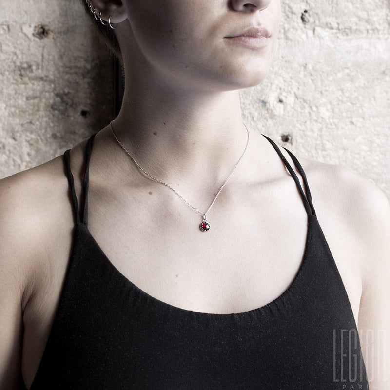 woman with short hair and black shirt wearing a white gold necklace with a garnet pendant 