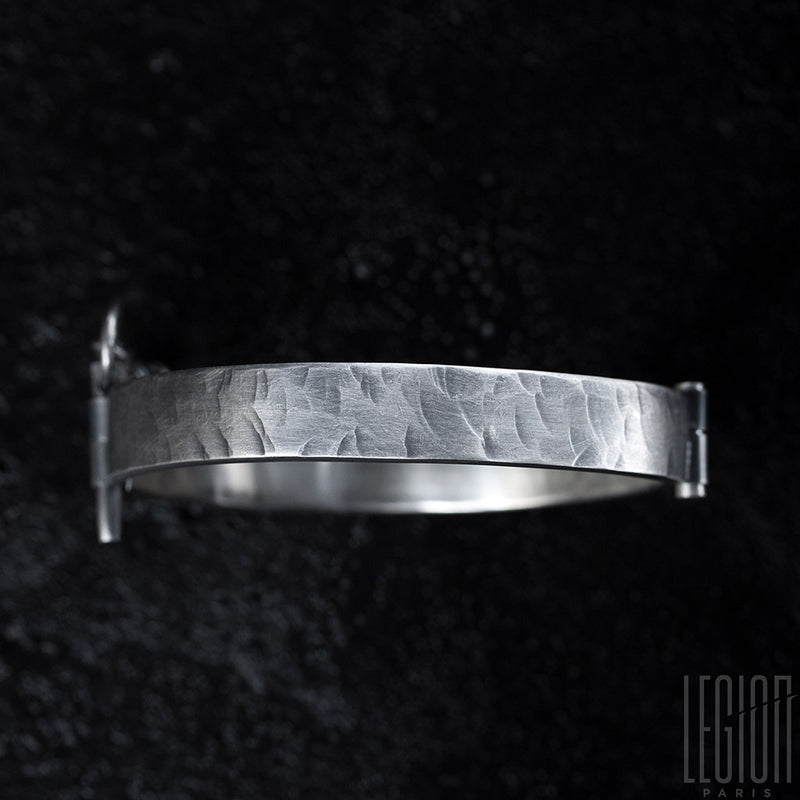 top view of a rigid black silver bracelet with a pin