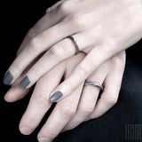 women's and men's hands wearing black silver textured wedding rings