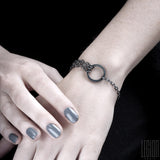 women's wrists wearing a black silver bracelet