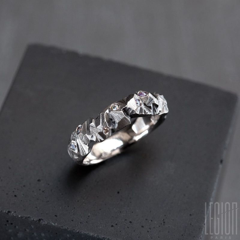 white textured gold ring with small round sapphires of different light colors scattered on it. 