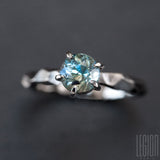 very close up of a white gold solitaire ring with a blue aquamarine stone
