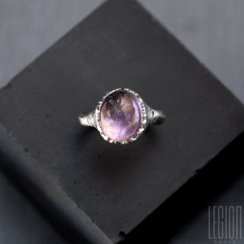 view from above of a white gold ring with an oval purple stone and two grey diamonds