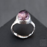 side view of a massive white gold ring with a large cabochon of mauve pink tourmaline set in close but with a ripped effect