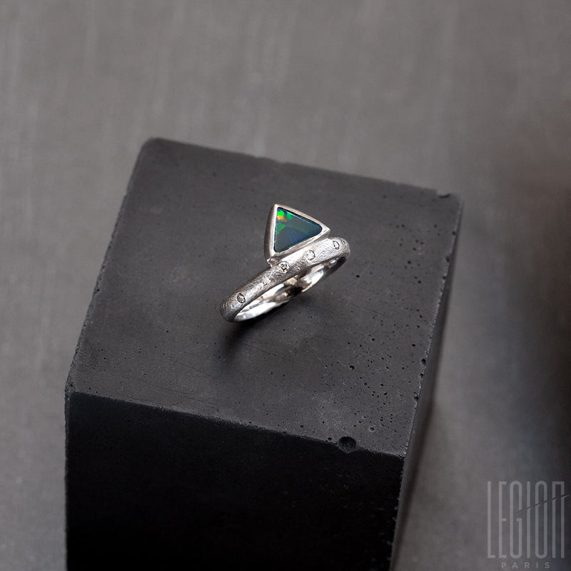 Textured white gold ring with randomly placed grey diamonds and a black triangle opal with green and orange lights