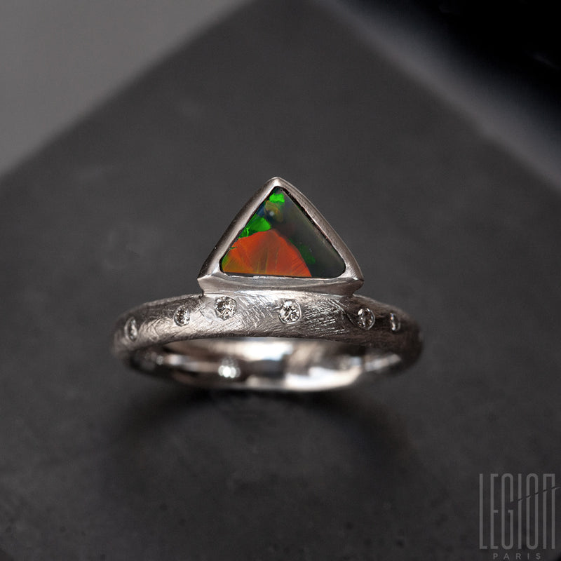 Textured white gold ring with randomly placed grey diamonds and a black triangle opal with green and orange lights
