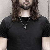 long-haired black man wearing a black t-shirt with a black silver bear head pendant