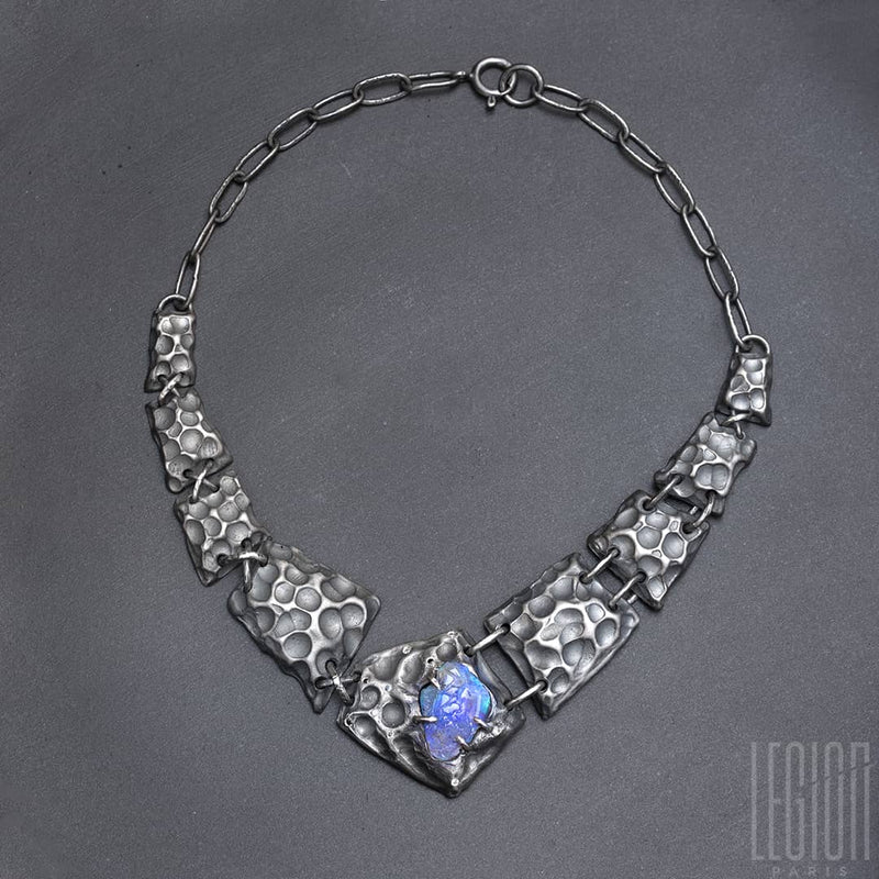 a black silver plastron necklace made of different textured black silver tiles with a raw black opal in the center