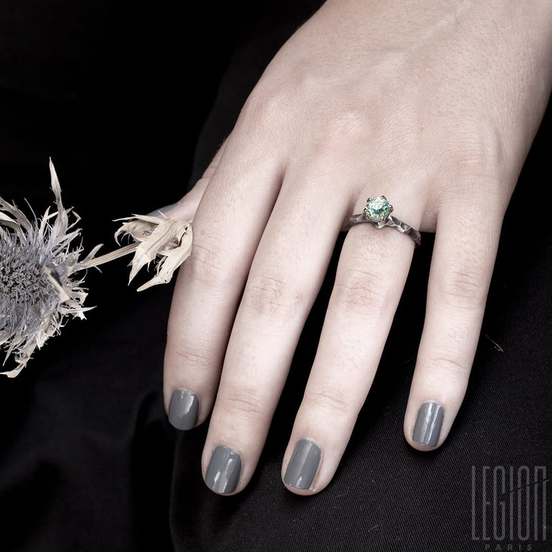 woman's hand wearing a white gold textured solitaire ring with a light blue aquamarine stone