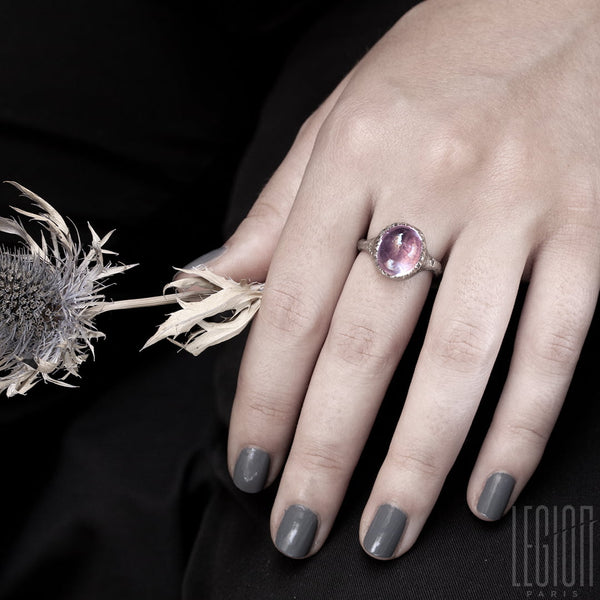 Woman's hand wearing a white gold textured signet ring with a large pink tourmaline cabochon set with small claws that look like an eggshell