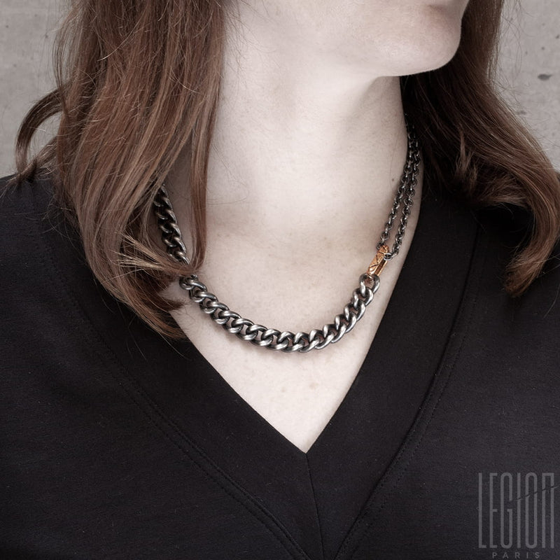 Redheaded woman wearing a solid black silver chain necklace with a rectangular red gold ring through which passes a double round black silver forçat chain