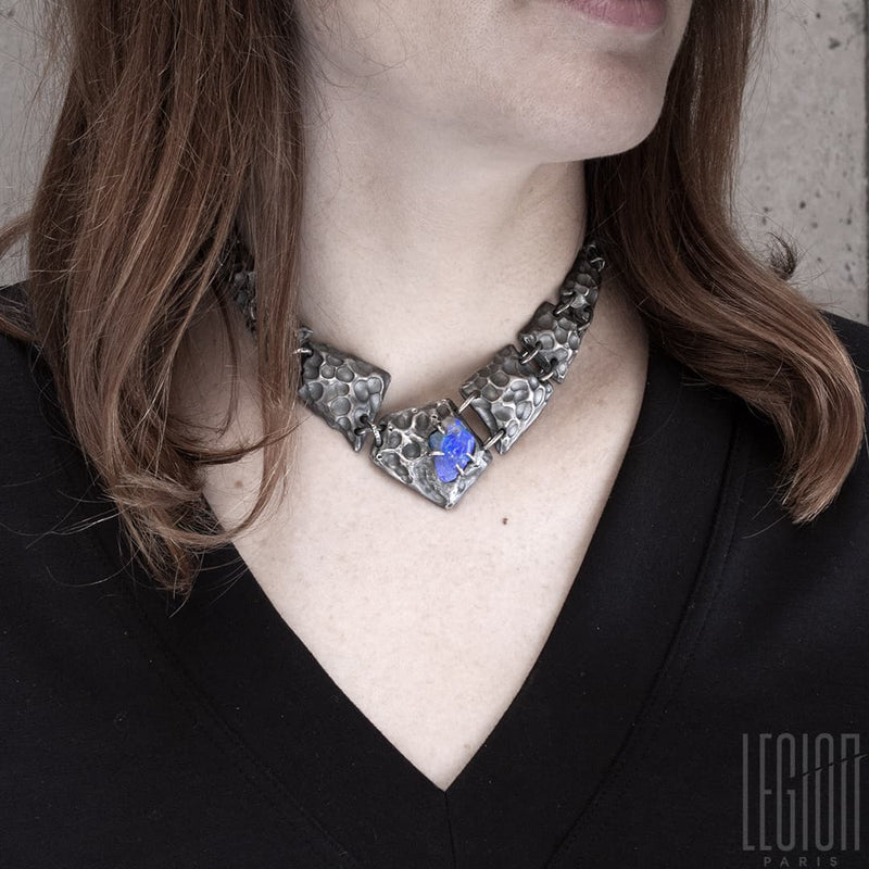 redheaded woman wearing a black tee shirt and a black silver necklace made of different textured black silver tiles with a raw black opal in the center