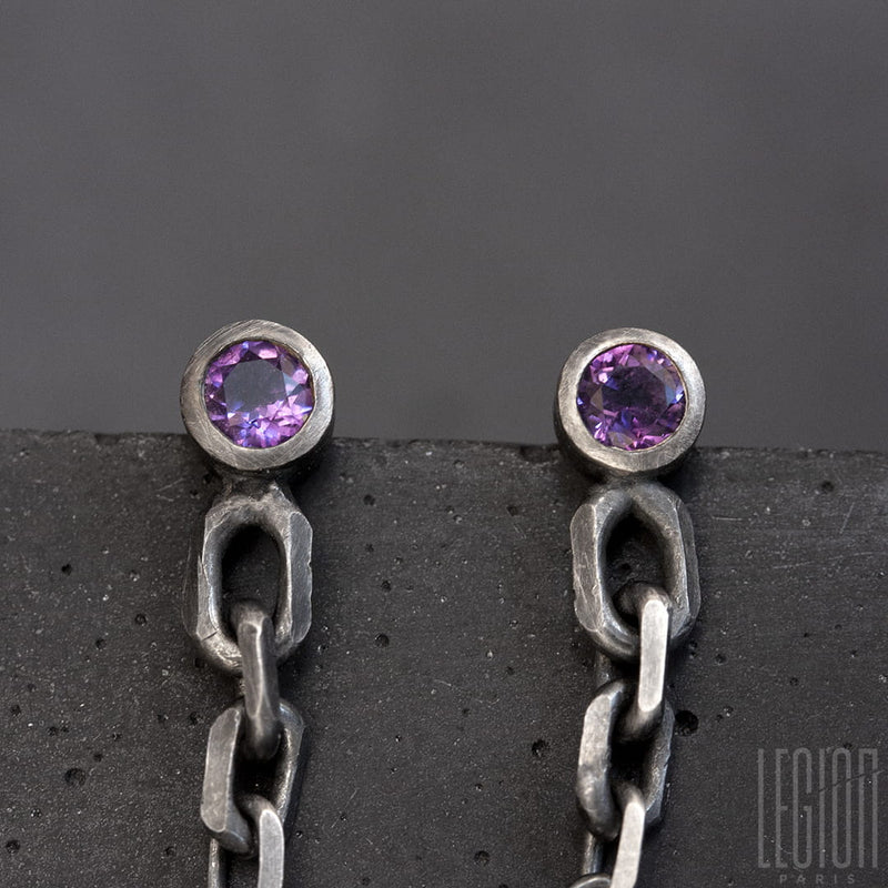 close-up of two round purple amethysts set in a closed setting with a black silver chain