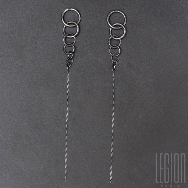 pair of black silver earrings, fall of rings ending on a long and light chain bracelet.
