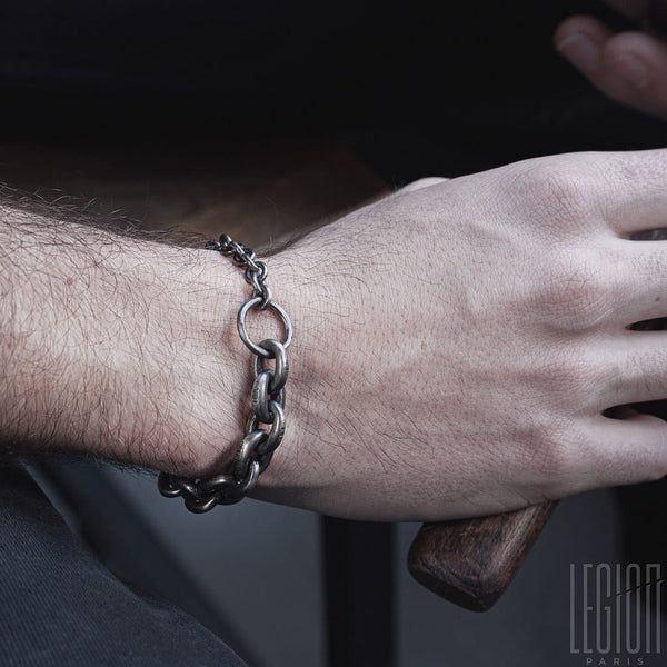 man's wrist wearing a black silver chain bracelet with large links and a ring