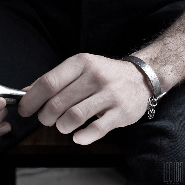 man's hand wearing a rigid black silver bracelet 