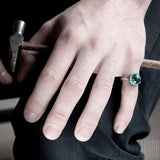 man's hand wearing a silver ring with a blue tourmaline