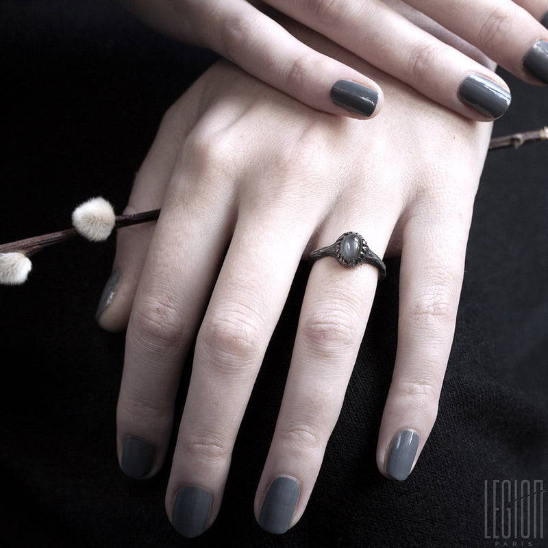 women's hands wearing a black silver ring with a grey moonstone