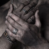 hands of man wearing several jewels in black silver, white gold, and red gold 
