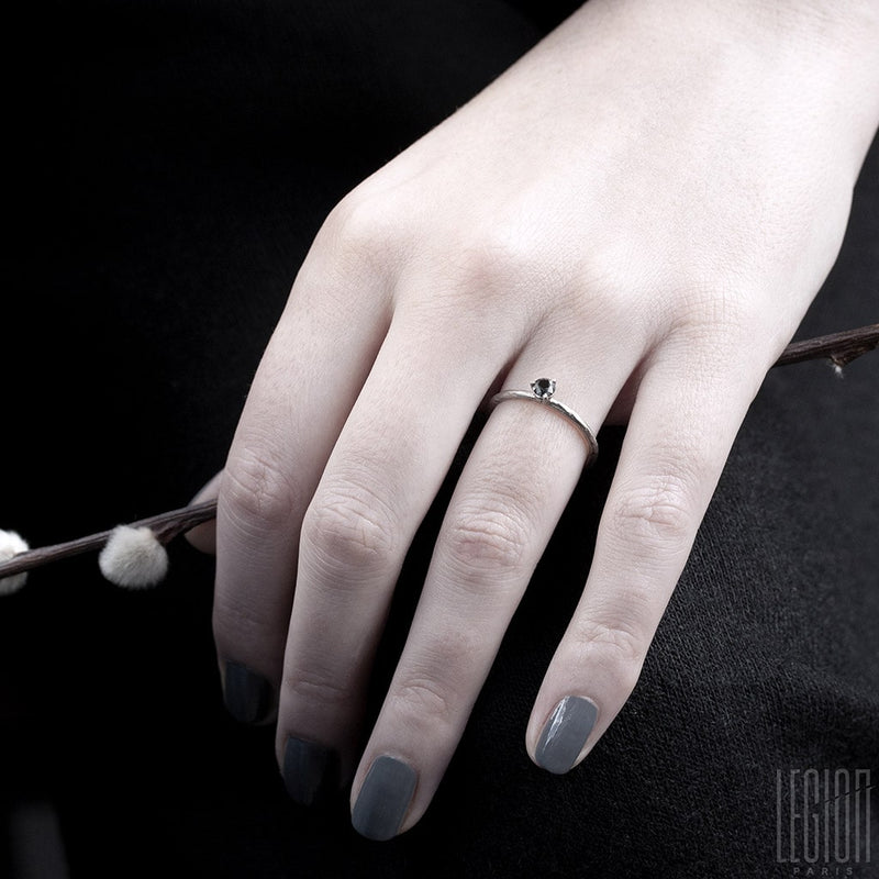 woman's hand wearing a white gold solitaire with a black diamond